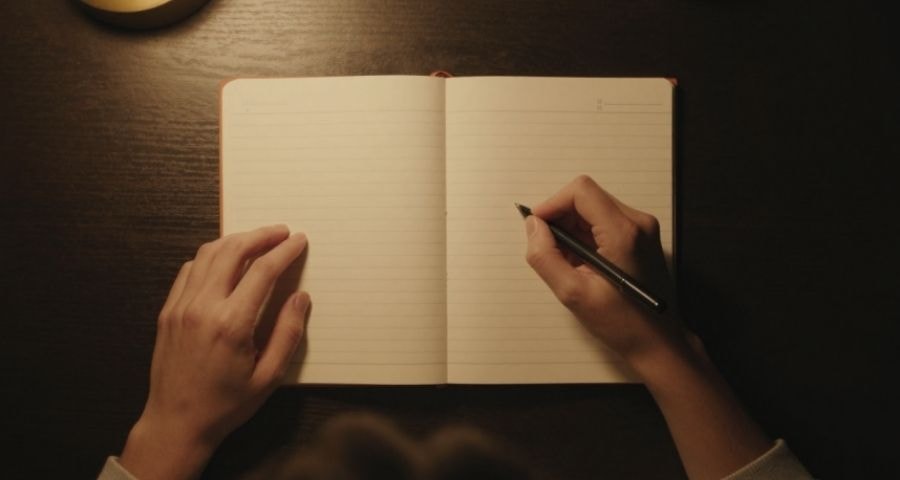 A woman journaling by warm morning light, writing with intention and mindfulness