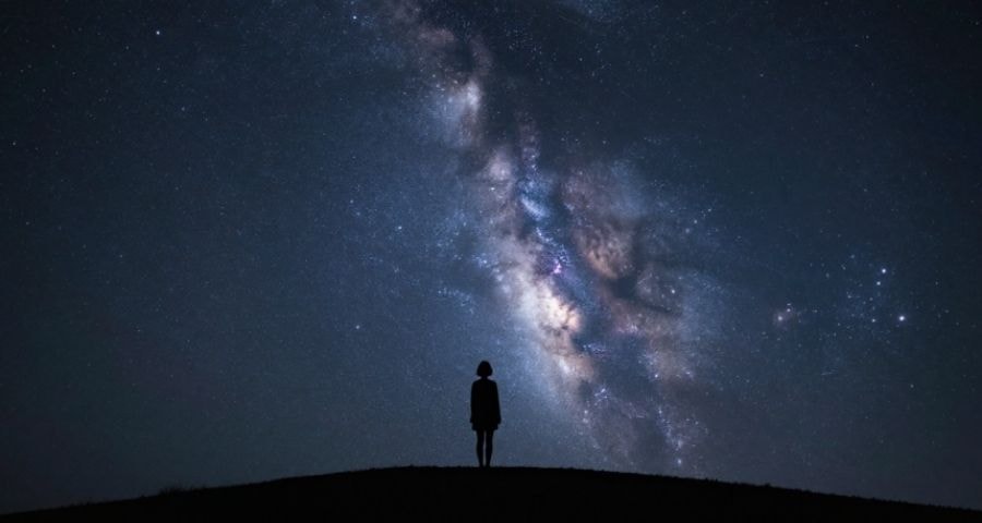 A woman gazing at the night sky, surrounded by stars and cosmos, a sense of wonder and healing